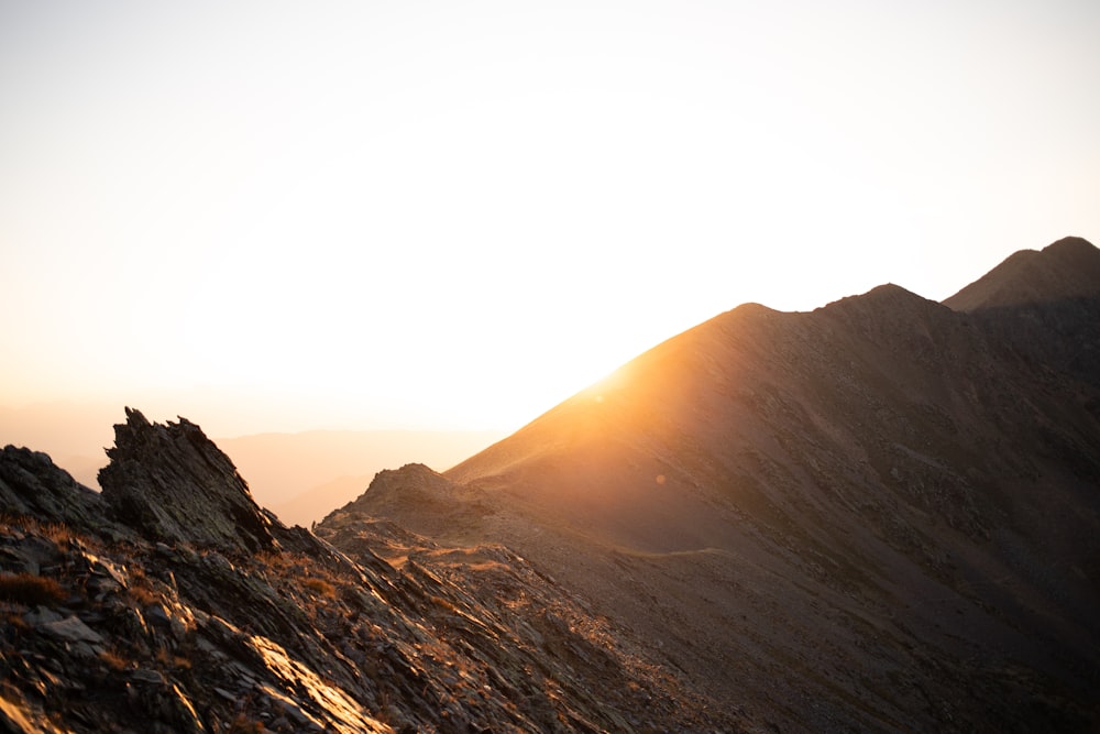 the sun is setting on a rocky mountain