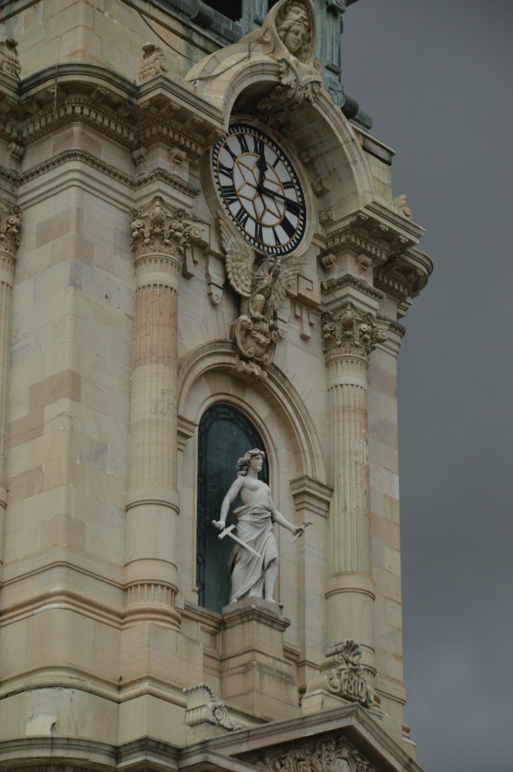 uma torre de relógio alta com uma estátua no topo dela