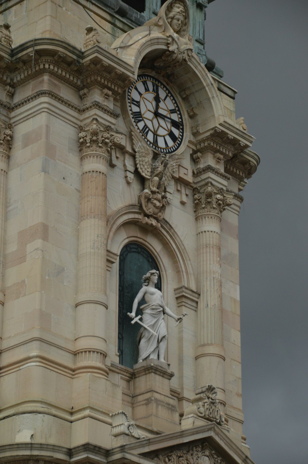 une haute tour de l’horloge surmontée d’une statue