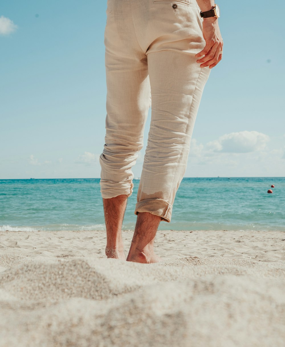 a man standing on a beach with his feet in the sand