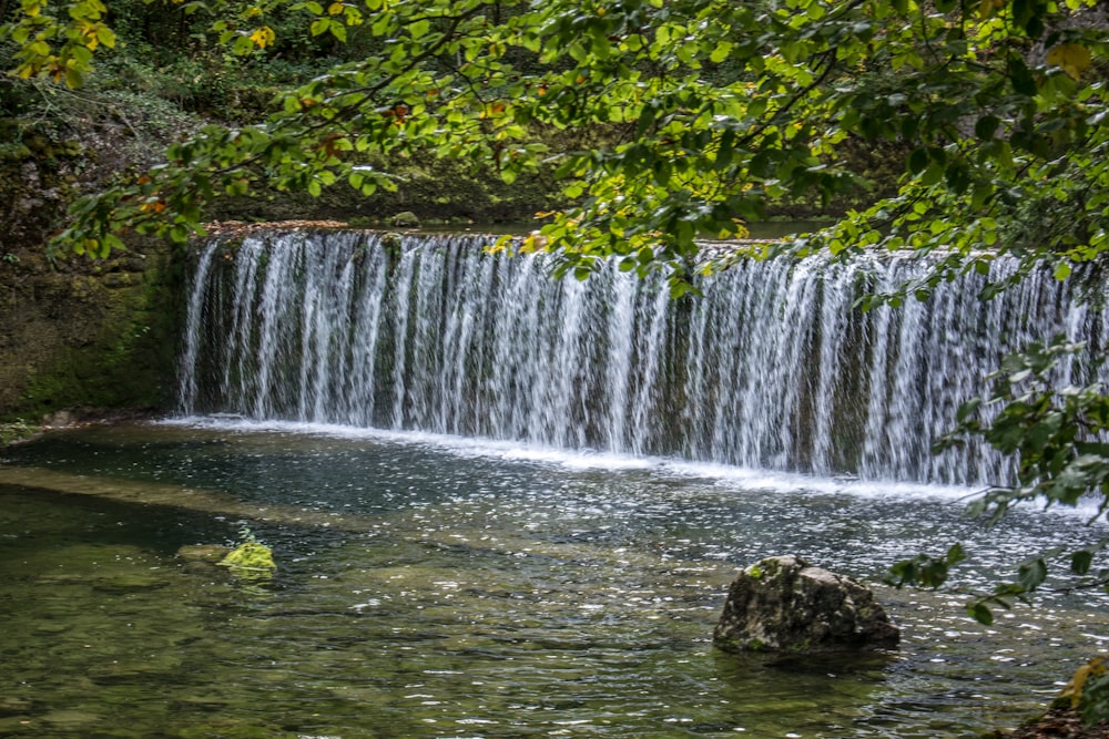 un homme debout dans un plan d’eau près d’une cascade