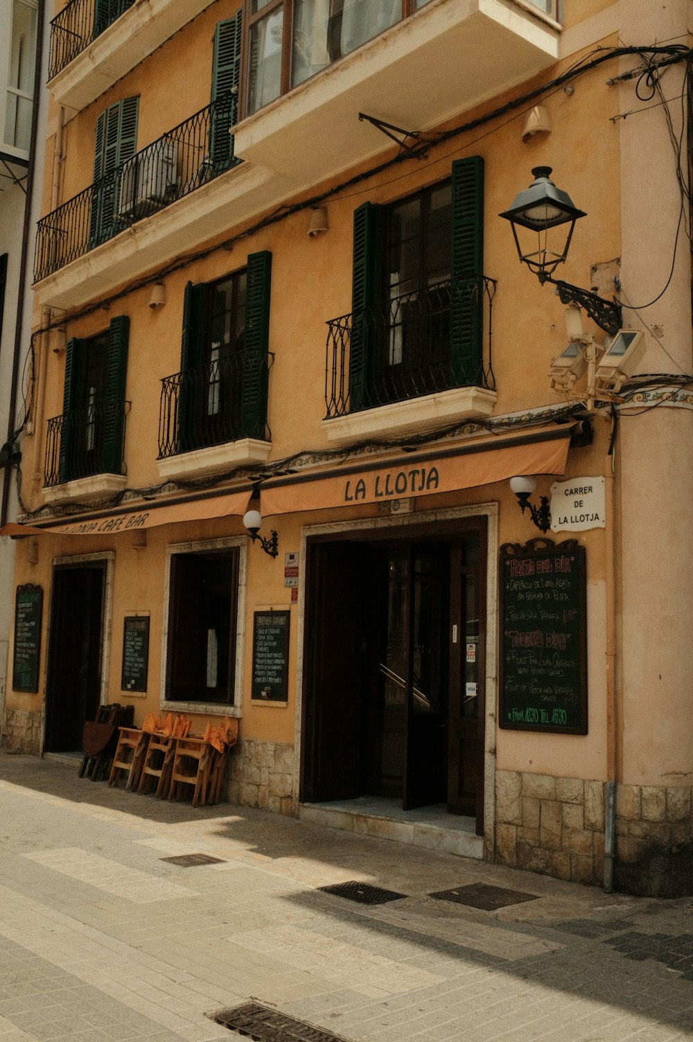 a yellow building with green shutters next to a sidewalk