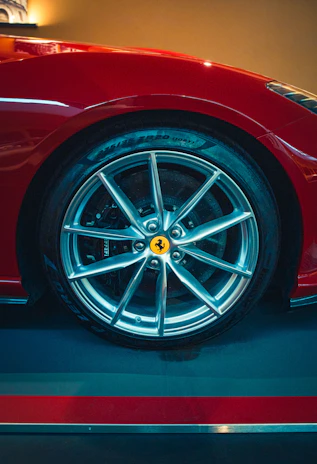 Close-up of a shiny red sports car wheel with the luksdrive logo reflected on the rim.