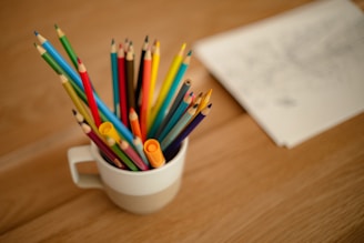 a cup filled with colored pencils on top of a wooden table