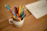 Close-up of a whimsical ceramic monster holding colorful pens on a wooden desk.