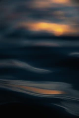 Soft-focus image of a calm ocean at dusk with subtle gold highlights.