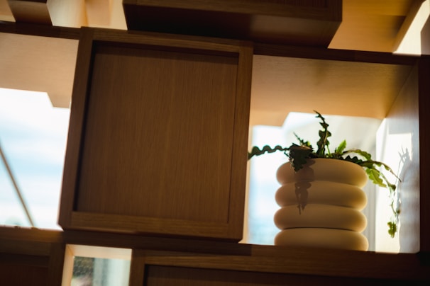 A set of plastic planters with minimalist designs, placed on a wooden shelf with natural light.