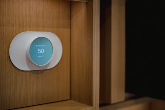 Close-up of a used smart thermostat mounted on a wall with a modern interior background.