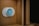 A modern, circular smart thermostat is mounted on a wooden wall. The device displays a message suggesting setup with Wi-Fi and shows the number 50, indicating an indoor temperature setting. The design appears sleek and minimalist.