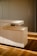 A modern, minimalist wooden cabinet with clean, sharp lines and a light wood finish. The cabinet is placed on a hardwood floor, with soft, natural light casting gentle shadows, enhancing the warm tones of the wood.