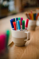 Close-up of vibrant pens and markers in a cup, ready for creative use.