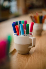 Close-up of vibrant pens and markers arranged in a cup, ready for creative use.