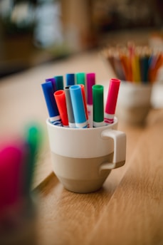 Round image of assorted vibrant pens in a cup