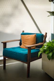 Modern teak wood lounge chair with soft cushions in natural light.
