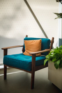 Luxurious teak wood armchair positioned in a sunlit modern living room.