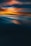 A serene abstract landscape featuring a dramatic blend of colors, with deep blues transitioning into warm hues of orange and soft pinks. The image creates an impression of a sunset or sunrise reflected on a smooth water surface, with soft blending and gentle waves creating a calming visual effect.