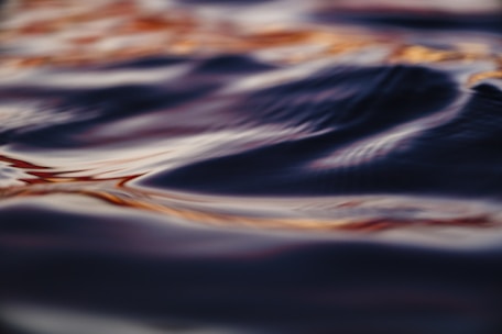 Close-up of gentle ripples on water surface reflecting ambient warm tones.