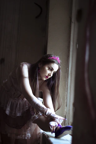 A serene backstage moment with Kristina tying her shoe, framed by soft sage curtains.