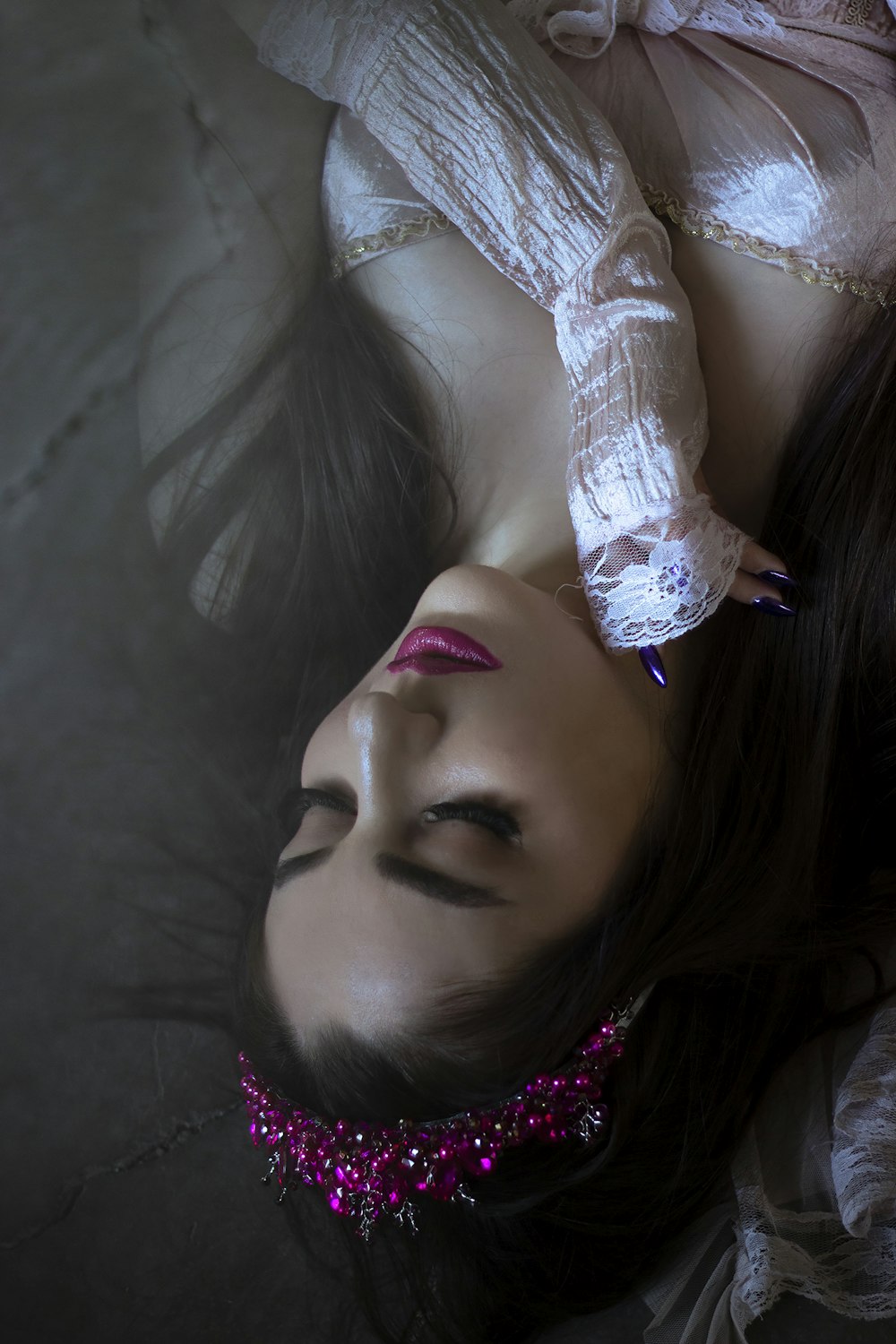 a woman laying on her back wearing a pink choker