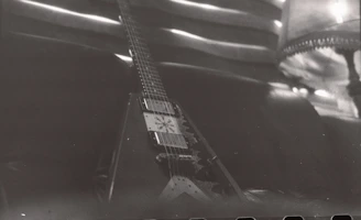 A sleek electric guitar resting against a deep blue velvet backdrop, illuminated by soft noir lighting.