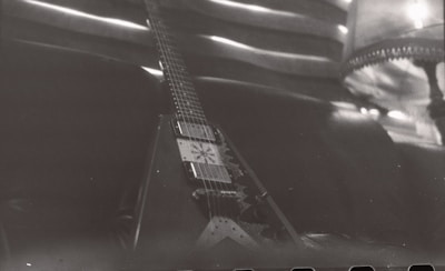 Vintage-style photo of an electric guitar resting on a dark wooden floor.