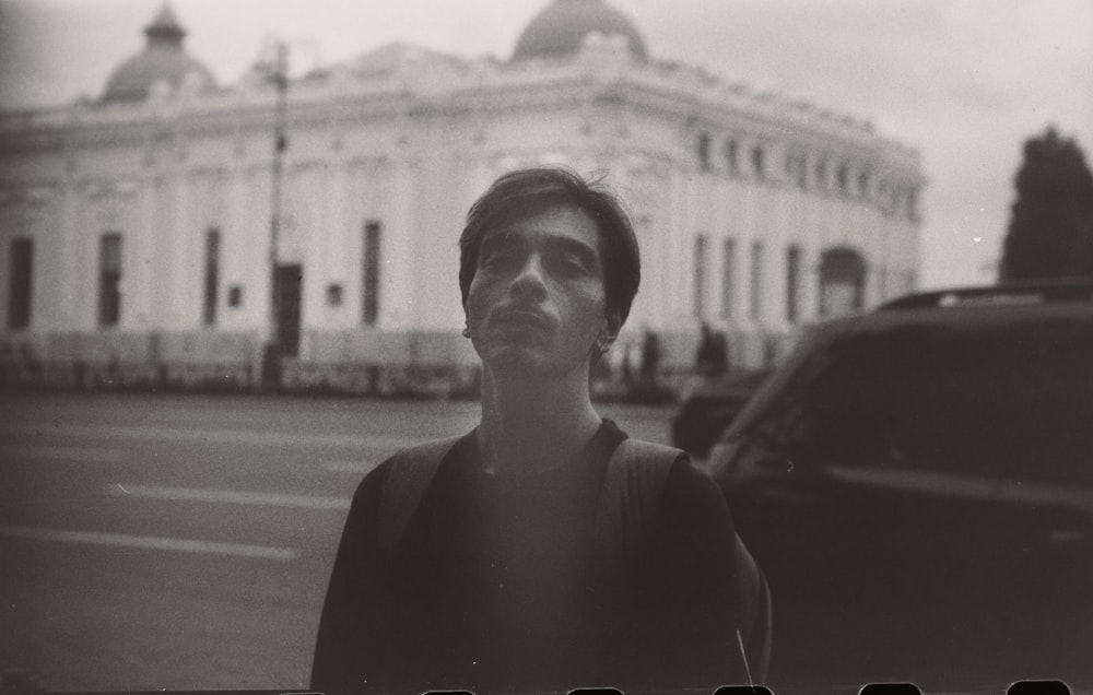 a black and white photo of a man standing in front of a building