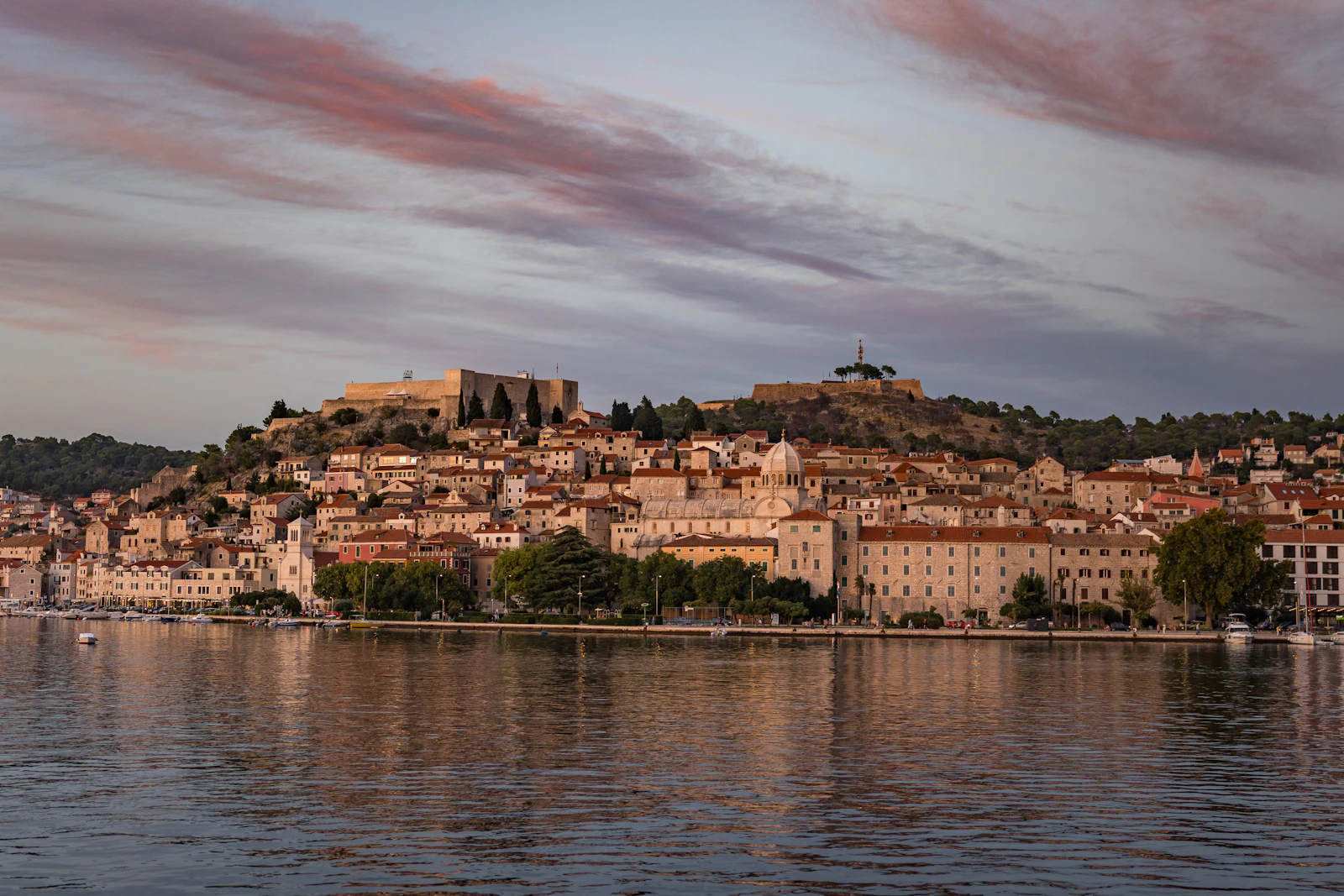 Šibenik u sumrak s mora: katedrala sv. Jakova i tvrđava sv. Mihovila iznad rive