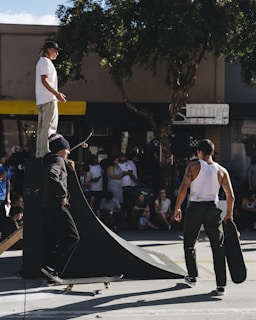 Group of kids gathered around a skate instructor demonstrating a new move.