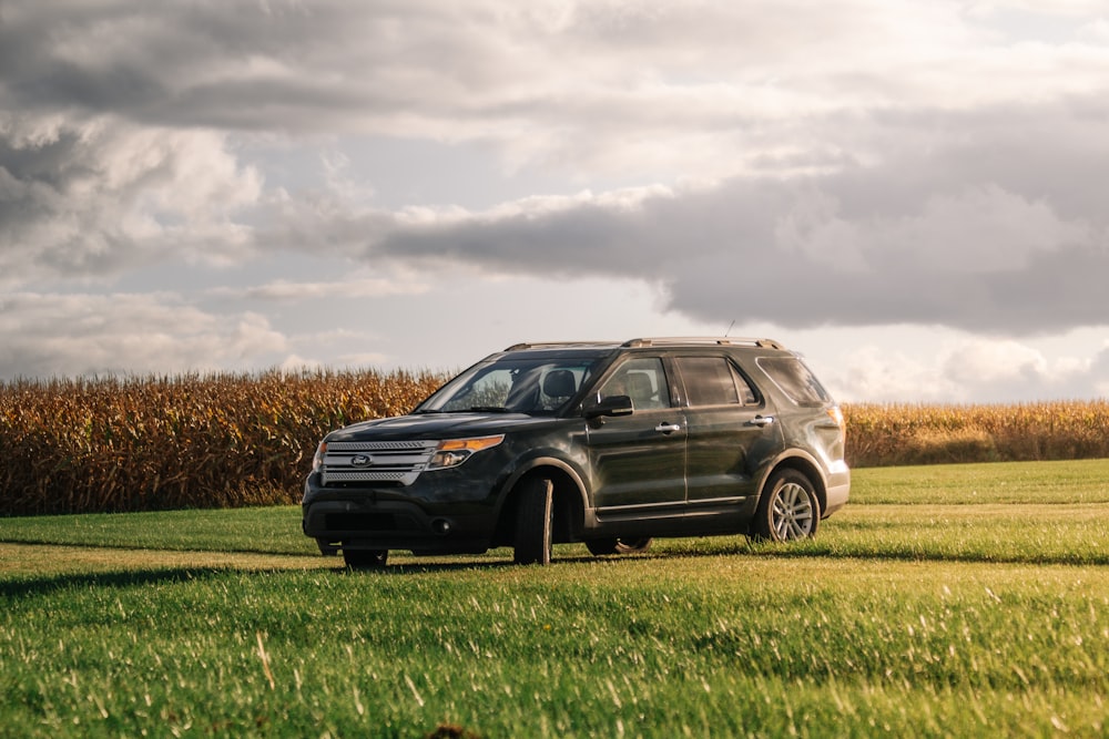 a black suv parked in a field of grass
