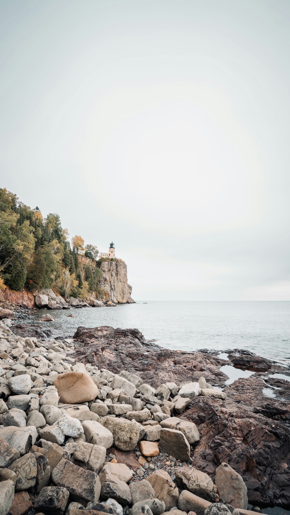 a rocky shore with a lighthouse in the distance