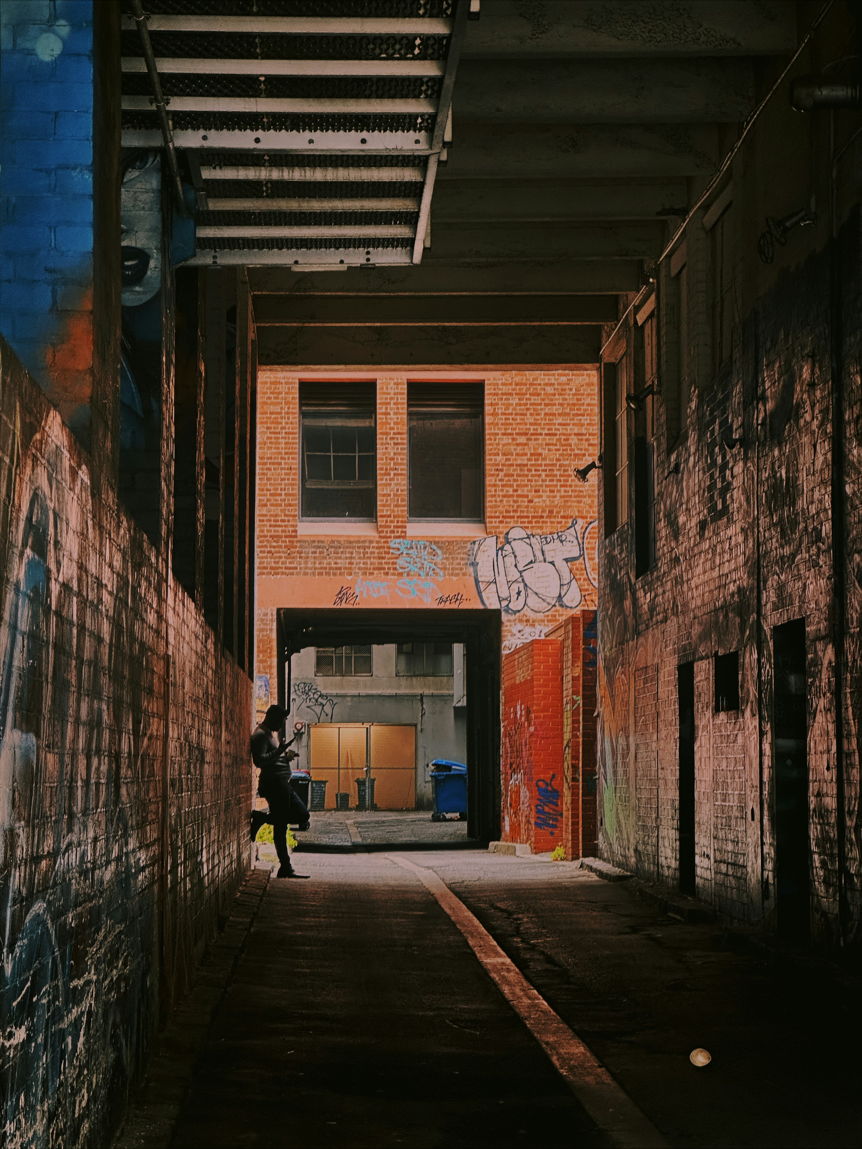 a person standing in an alley with graffiti on the walls