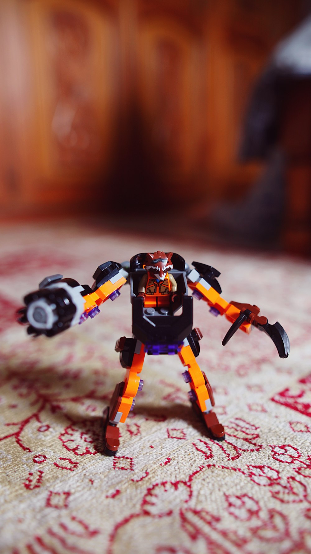 a small toy robot on a bed with a red and white bedspread