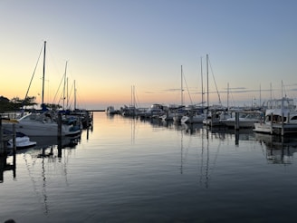A peaceful marina at sunset with boats docked along wooden piers.