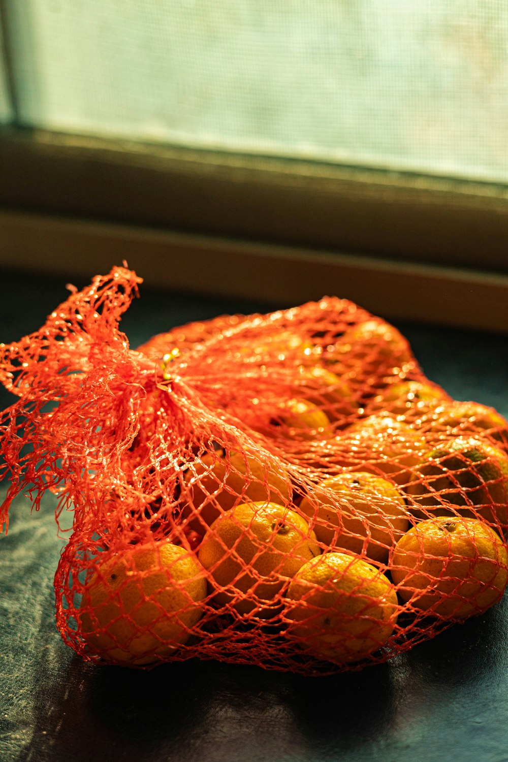 a mesh bag filled with oranges sitting on top of a counter