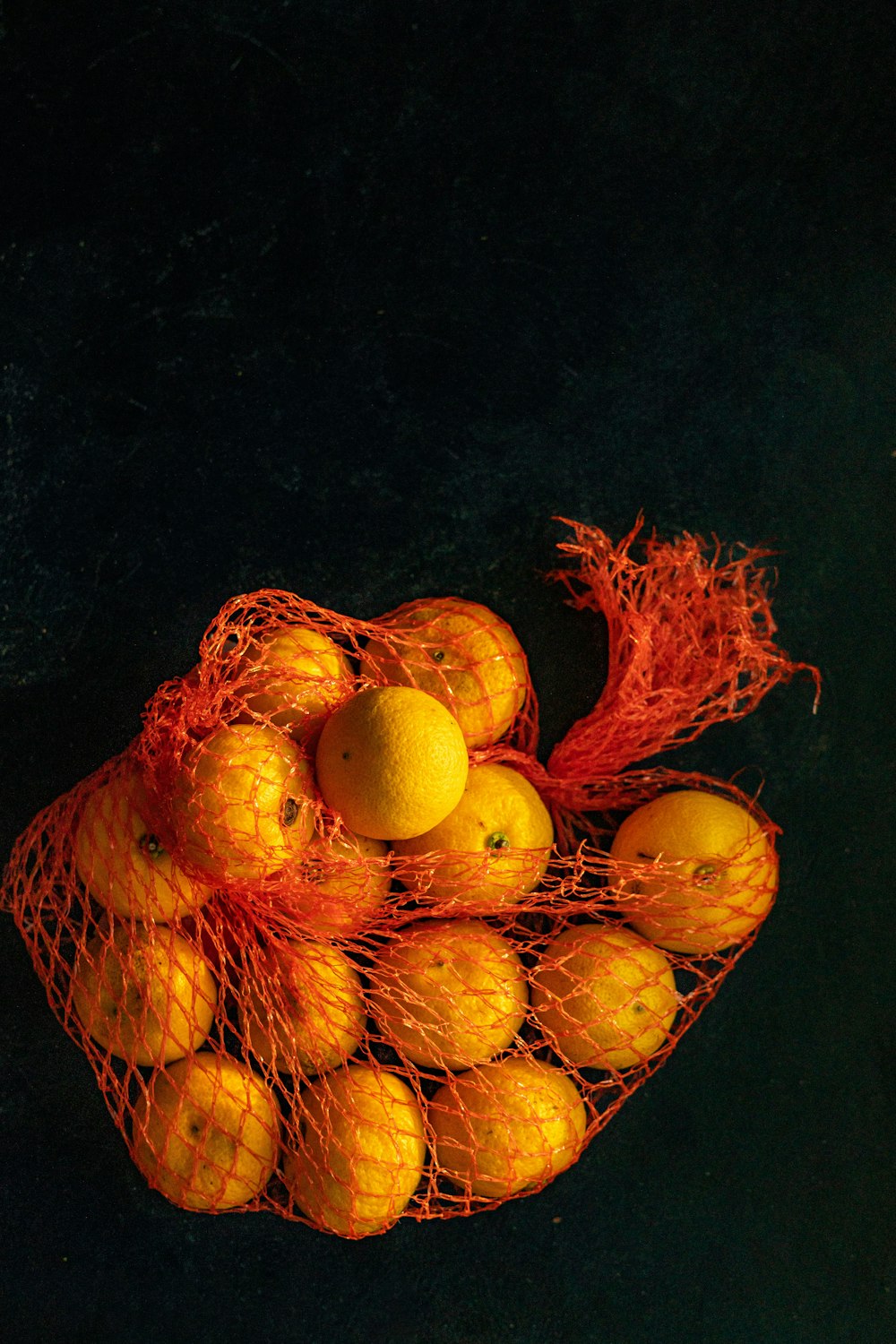 a bunch of oranges sitting in a net bag