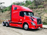 Truck driver checking paperwork beside a red-accented truck.
