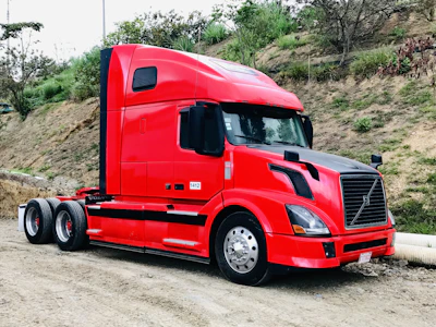 Truck driver checking paperwork beside a red-accented truck.
