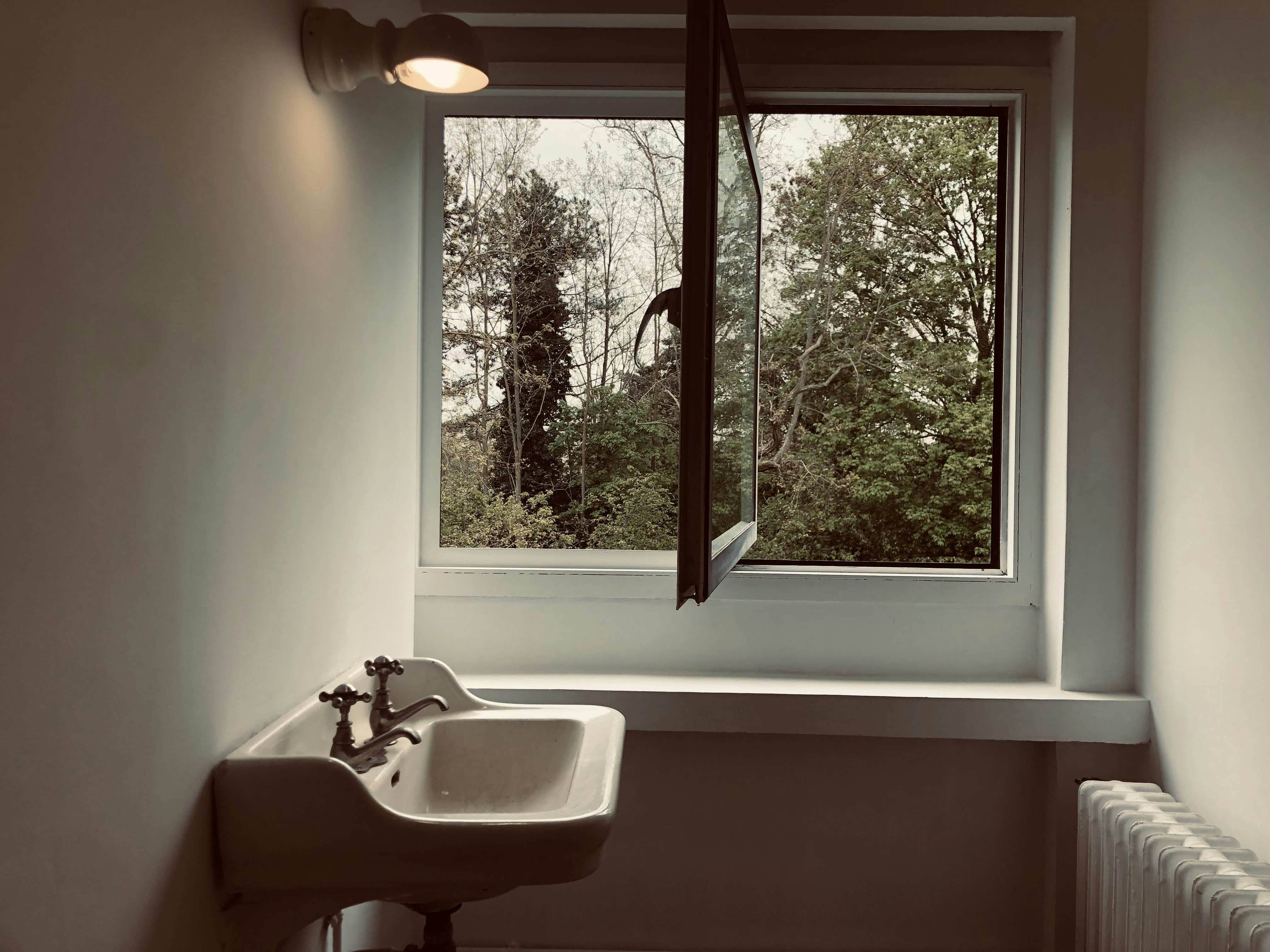 a white sink sitting under a window next to a radiator