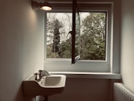 Shiny steel radiator mounted under a window in a bright, minimalist kitchen.