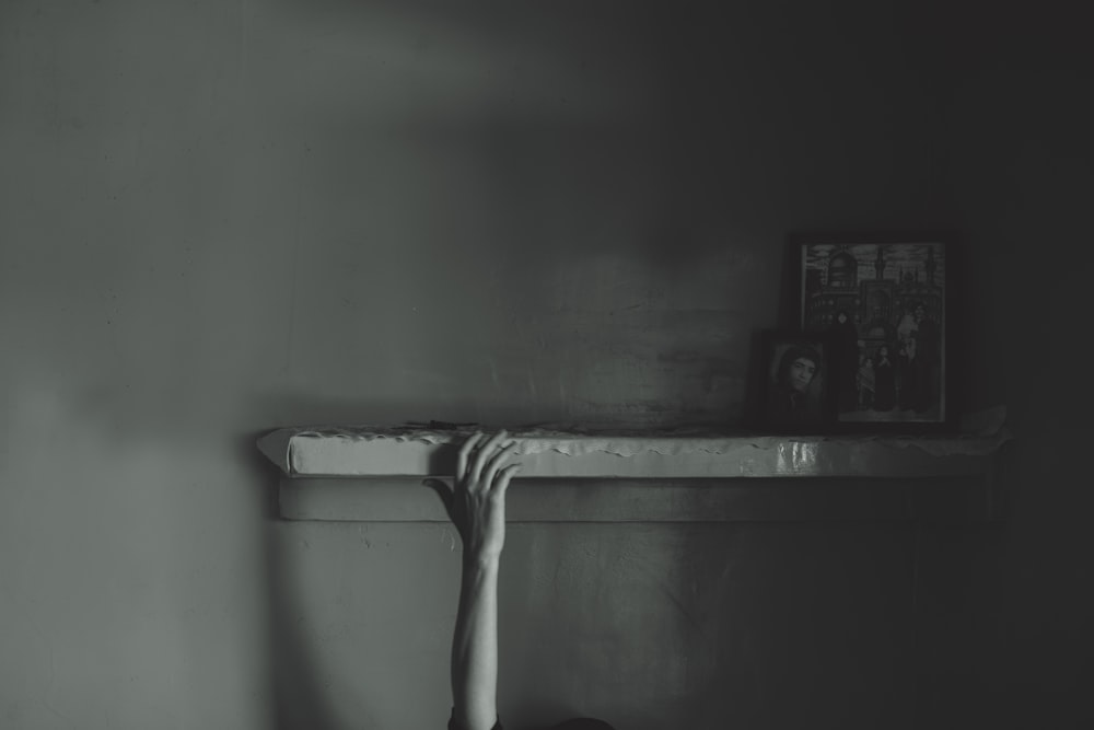a black and white photo of a person's hand on a shelf