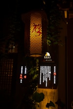 A warm lantern hanging beside a crescent moon against a dark green background.