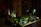 An indoor scene with a variety of small potted plants arranged on a table. The setting is dimly lit, creating a cozy atmosphere. Some decorative items hang from a large vase, adding to the aesthetic. A few small light sources are visible, casting gentle illumination on the plants and creating soft shadows.