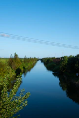 An engineer examining a detailed floodplain map beside a flowing river under a clear blue sky.