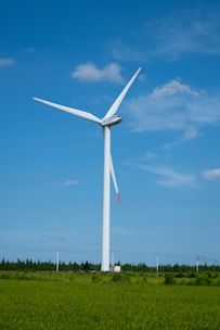 Technicians installing a wind turbine blade against a backdrop of green fields.