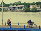 A group of e-bikers riding along a riverside path.