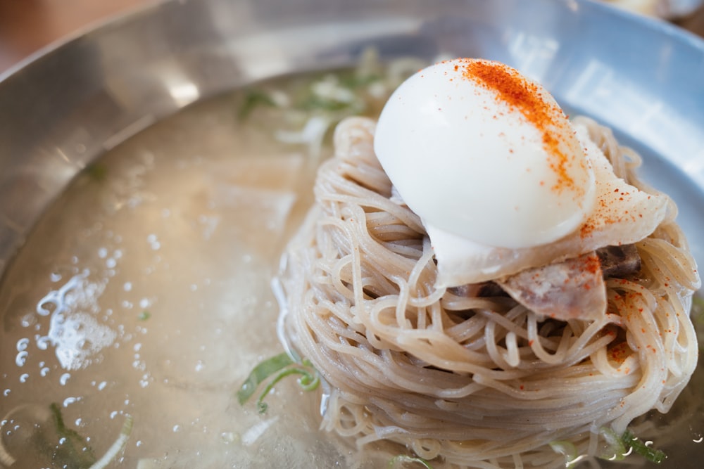 a plate of noodles with an egg on top