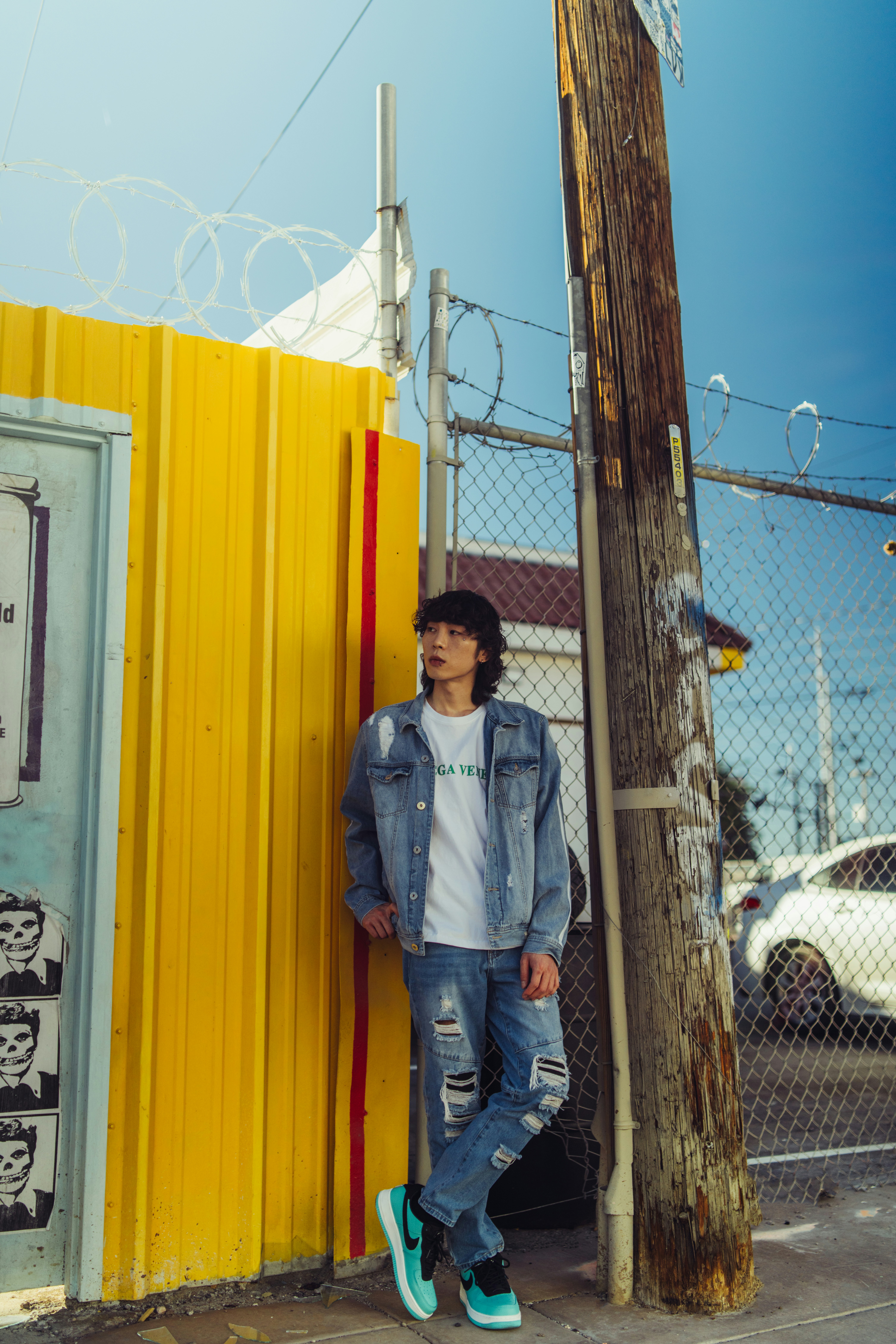 a young man leaning against a yellow fence