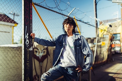 Model wearing skank wear streetwear jacket leaning against a graffiti-covered wall.