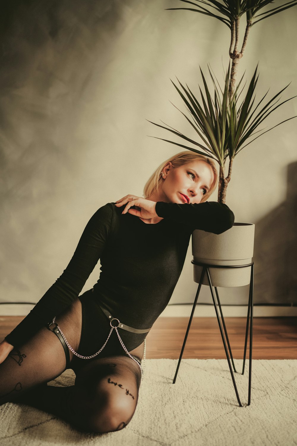 a woman sitting on the floor next to a potted plant