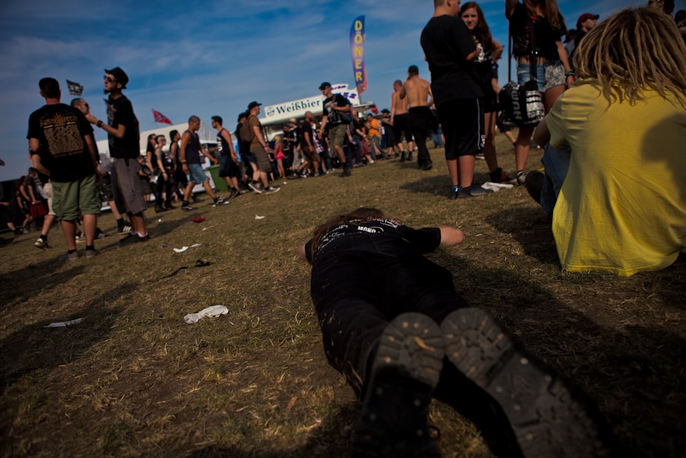 a crowd of people sitting on top of a grass covered field